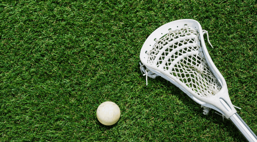 a lacrosse stick and ball on artificial sports turf