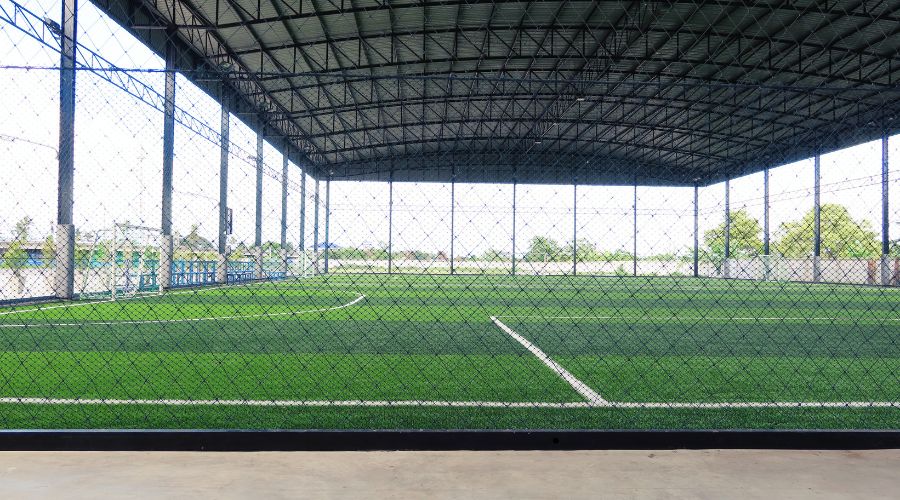 indoor sports facility with large protective netting system over synthetic turf field